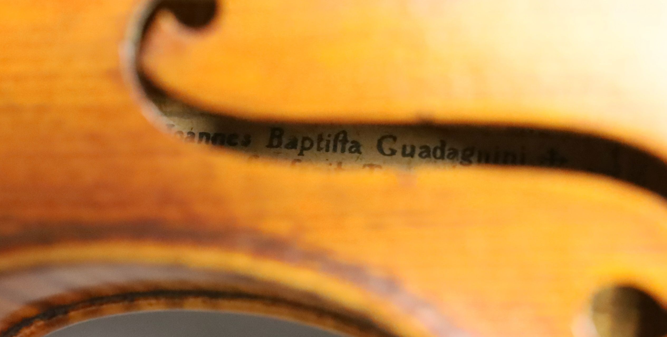 A 19th century violin labelled JB Guadagnini, back measures 35cm, with two bows, one silver-mounted.